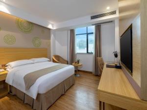a bedroom with a large bed and a flat screen tv at GreenTree Inn Zhongshan West District Fuhua Road Hotel in Zhongshan