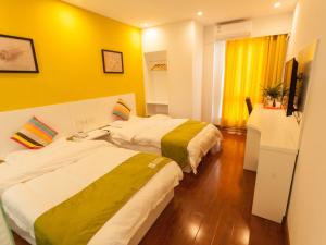 two beds in a hotel room with yellow walls at Shell Hefei Economic Development Zone Hong Kong and Macao Square Hotel in Hefei