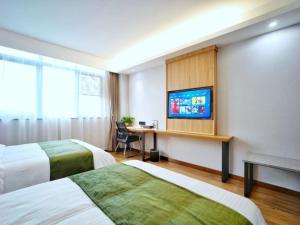ein Hotelzimmer mit 2 Betten und einem Schreibtisch mit einem TV in der Unterkunft GreenTree Inn Changzhou Xuebu Eastern Salt Lake City in Changzhou