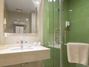 a green bathroom with a sink and a shower at GreenTree Inn Chengde Shuangluan District Xinhui Wan Business Hotel in Chengde