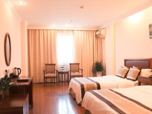 a hotel room with two beds and a table and chairs at GreenTree Inn Jiangsu Yangzhou Yizheng East Zhenzhou Road Express Hotel in Yizheng