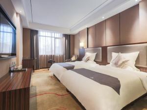 um grande quarto de hotel com duas camas e uma televisão em GreenTree Eastern Ganzhou City Zhanggong DistrictEight one four Avenue bus station Hotel em Ganzhou