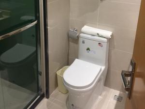 a bathroom with a toilet and a glass shower at Vatica Xingtai Qiaoxi District Yongkang Street Technical College Hotel in Xingtai
