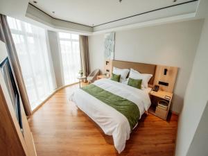 ein Schlafzimmer mit einem großen Bett und einem großen Fenster in der Unterkunft GreenTree Inn Taizhou Xinghua City Zhouzhuang Town Business Hotel in Taizhou