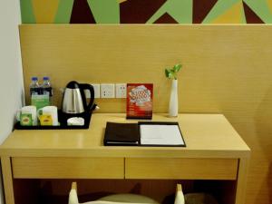 einen Holztisch mit einem Schreibtisch, einem Wasserkocher und einer Schachtel in der Unterkunft Vatica Xuzhou Suining Bus Station Building Materials City Hotel in Sui-ning-hsien