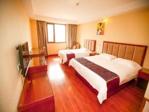 a hotel room with two beds and a television at GreenTree Inn Shandong Qingdao Wuyishan Road Jiashike Shopping center Business Hotel in Huangdao