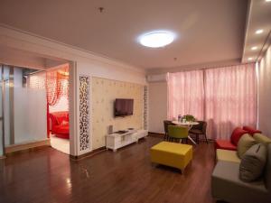 a living room with a couch and a table and a tv at GreenTree Inn Langfang Dacheng County Donghuan Road Express Hotel in Daicheng