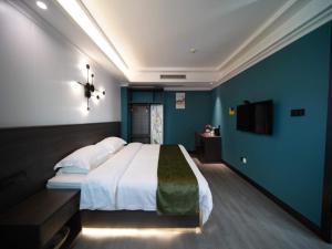 een slaapkamer met een groot bed en een blauwe muur bij GreenTree Alliance JiangXi ShangRao YiYang County ZhiMin Aveune YingBin Avenue Hotel in Yiyang