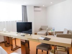a living room with a desk with a television on it at GreenTree Inn HuaiAn Huaiyin Area The Yangtze River East Road Express Hotel in Huai'an