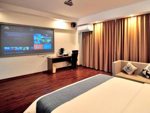 a hotel room with a bed and a flat screen tv at GreenTree Inn Dongfang City Dongfang Avenue High-speed Railway Station Express Hotel in Dongfang