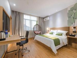 a bedroom with a large bed and a desk and a desk at Shell Ningbo Gaoqiao Subway Station Hotel in Ningbo