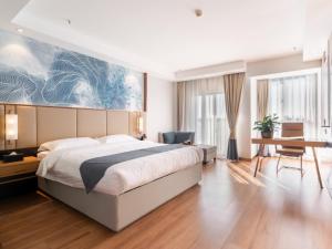 a bedroom with a large bed and a desk at GreenTree Inn Jiangsu Wuxi Hudai FuAn Commercial Plaza Business Hotel in Chang-she-chen