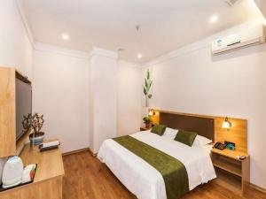 a bedroom with a large bed and a television at GreenTree Inn Dalian Airport New District Xinzhaizi Express Hotel in Dalian
