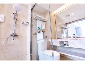 uma casa de banho com um chuveiro, um WC e um lavatório. em GreenTree Inn Fuyang Linquan County Economic Development Zone Xingye Road Hotel em Fuyang