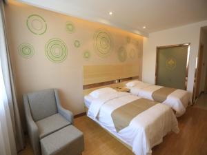 duas camas num quarto com uma cadeira em GreenTree Inn Anqing City Yixiu Government District University City Express Hotel em Anqing