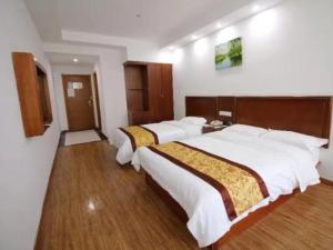 two beds in a hotel room with wooden floors at GreenTree Inn Jiangsu Changshu City Longying Square Express Hotel in Changshu +6 photos