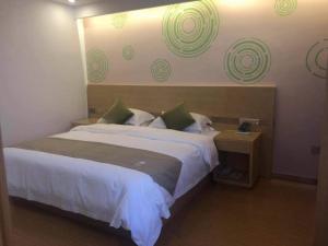 a bedroom with a large white bed with green accents at GreenTree Inn Lanzhou Yuzhong County Business Hotel in Lanzhou