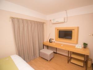 a room with a desk with a television on it at Green Alliance Chengde City Shuangqiao District Summer Resort Hotel in Chengde