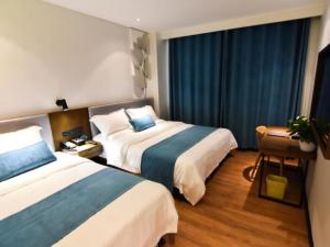 two beds in a hotel room with blue curtains at GreenTree Rizhao Lanshan Coach Station Hotel in Rizhao