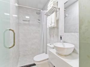 a white bathroom with a toilet and a sink at Shell Hefei Qingyang North Road 901 Hospital Hotel in Hefei
