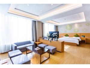 a hotel room with a bed and a living room at GreenTree Inn Fuyang Linquan County Economic Development Zone Xingye Road Hotel in Fuyang +12 photos