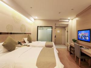 um quarto de hotel com duas camas e uma secretária e uma televisão em GreenTree Inn Wuxi Yixing High-speed Railway Station Dingshu Town Tongshu Road Express Hotel em Wuxi