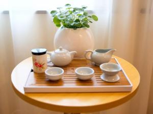 a tray with tea sets and a vase on a table at GreenTree Inn Zhejiang Shaoxing Xinchang Buddha Express Hotel in Xinchang