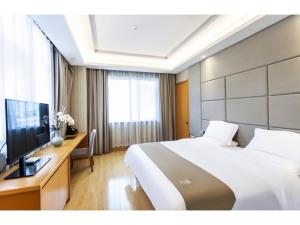 een slaapkamer met een bed en een bureau met een televisie bij GreenTree Inn Fuyang Linquan County Economic Development Zone Xingye Road Hotel in Fuyang