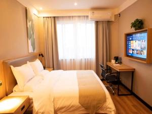 a hotel room with a bed and a desk and a television at GreenTree Inn Suzhou Railway Station Park Road Hotel in Suzhou