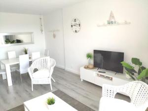 a white living room with a tv and a table at Atico Condal in Blanes