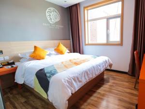 a bedroom with a bed and a desk and a window at Shell Zhangjiakou City Qiaodong District Ginza Hotel in Zhangjiakou