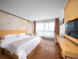 a bedroom with a large bed and a flat screen tv at GreenTree Inn Yancheng National Fitness Center Express Hotel in Yancheng