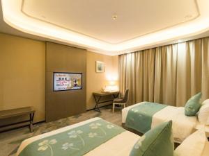 a hotel room with two beds and a television at GreenTree Eastern Wuxi Xinwu District Airport Road Hotel in Wuxi