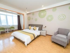 a large bedroom with a bed and a chair at GreenTree Inn Binzhou Yangxin County Bus Station Lubei Da Market Business Hotel in Binzhou