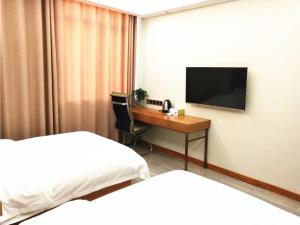 DonghaiにあるShell Lianyungang Donghai County Crystal City Shichen Road Hotelのデスクとテレビが備わるホテルルームです。