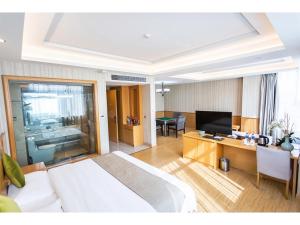 una camera d'albergo con letto, scrivania e TV di GreenTree Inn Fuyang Linquan County Economic Development Zone Xingye Road Hotel a Fuyang