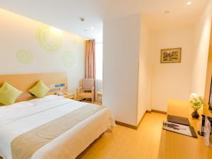 une chambre d'hôtel avec un grand lit et un bureau dans l'établissement GreenTree Inn Huzhou Zhili Fortune Plaza Wuxing Avenue Express Hotel, à Huzhou