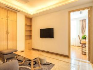 uma sala de estar com uma mesa e uma televisão na parede em GreenTree Inn Tangshan Road North District Xishan Road Business Hotel em Tangshan
