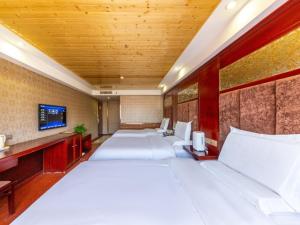 a room with a row of beds and a tv at GreenTree Inn Lanzhou Railway Station East Road Business Hotel in Lanzhou