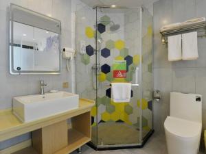 een badkamer met een wastafel en een douche bij Vatica Huanggang Luotian County City Square Hotel in Luotian