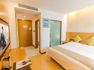 - une chambre avec un lit et un bureau avec un téléphone dans l'établissement GreenTree Inn Huzhou Zhili Fortune Plaza Wuxing Avenue Express Hotel, à Huzhou