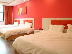 a hotel room with two beds and a red wall at Shell Fuzhou Nancheng County Railway Station Shengli West Road Hotel in Nancheng