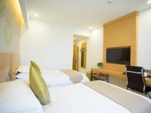 a hotel room with three beds and a television at GreenTree Inn Huai Nan Shou County Zijin Road Express Hotel in Majiaxu