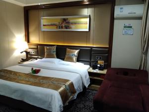 ein Hotelzimmer mit einem großen Bett und einem Stuhl in der Unterkunft GreenTree Alliance Xinyang Pingqiao District Nanjing Road Dongyang Hotel in Xinyang