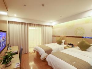 a hotel room with two beds and a flat screen tv at GreenTree Inn Wuxi Yixing High-speed Railway Station Dingshu Town Tongshu Road Express Hotel in Wuxi