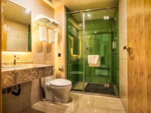 a bathroom with a toilet and a glass shower at GreenTree Inn Tangshan Road North District Xishan Road Business Hotel in Tangshan