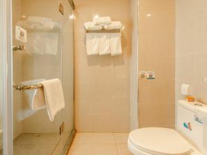 a bathroom with a toilet and a shower with towels at GreenTree Inn LiuAn Huoshan County Yingjia Avenue County Hospital Express Hotel in Huoshan