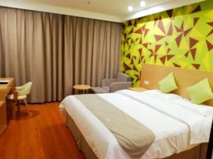 um quarto de hotel com uma cama, uma secretária e uma cadeira em Vatica Xuzhou Suining Bus Station Building Materials City Hotel em Suining