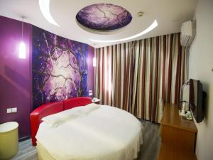 a bedroom with a white bed and a purple wall at Shell Binzhou Bincheng District Yellow River Four Road Hotel in Binzhou