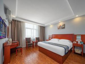une chambre d'hôtel avec un grand lit et un bureau dans l'établissement GreenTree Inn JiangSu YanCheng North Bus Station Bolian Plaza Business Hotel, à Yancheng